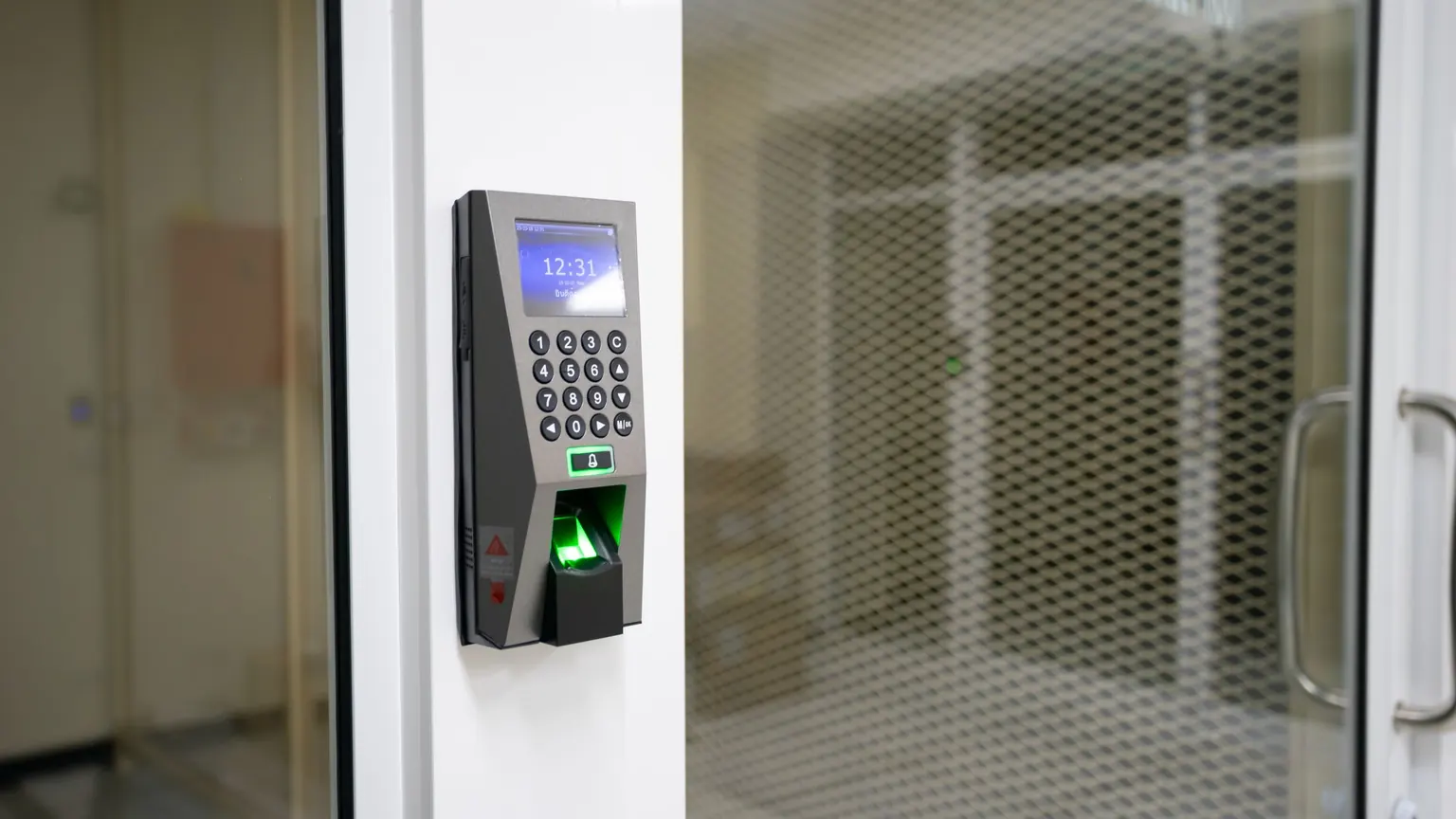 Máy chấm công vân tay gắn cạnh cửa kính, màn hình hiện 12:31